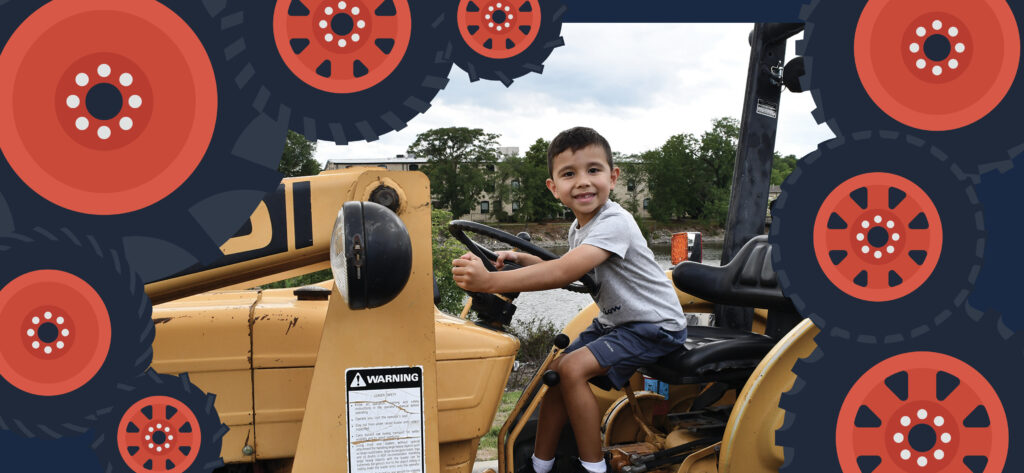 Little boy smiling while sitting on a tractor during a touch a truck event