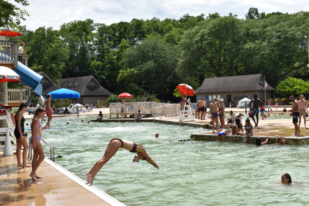 A girl dives off the side of the wall into the water at Hall Quarry Beach