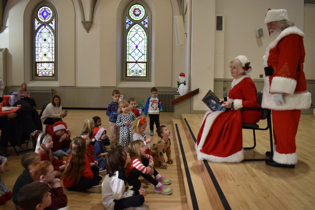 Mrs. Claus and Santa are shown reading a book to children at Breakfast with Santa.