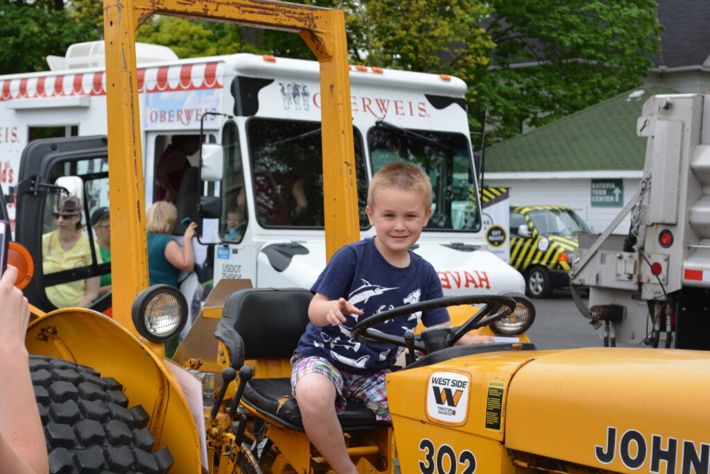 A boy plays on a tractor during a touch a truck event