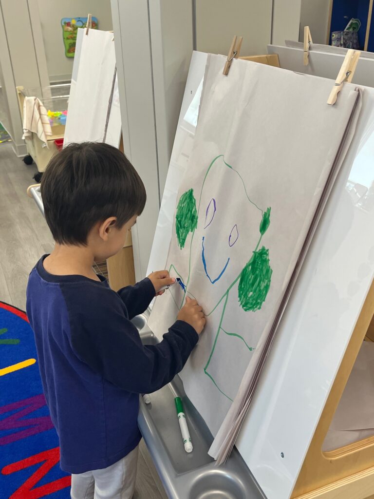 A student stands in front of an easel drawing a figure