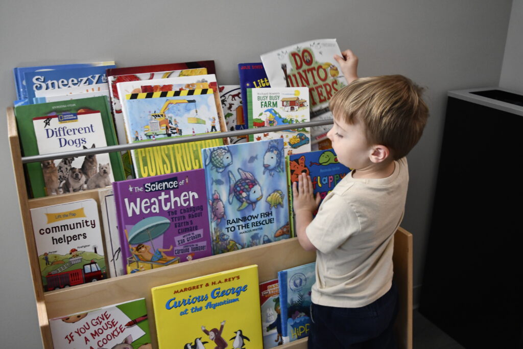 A young student selects their book for independent reading time during PlayLab