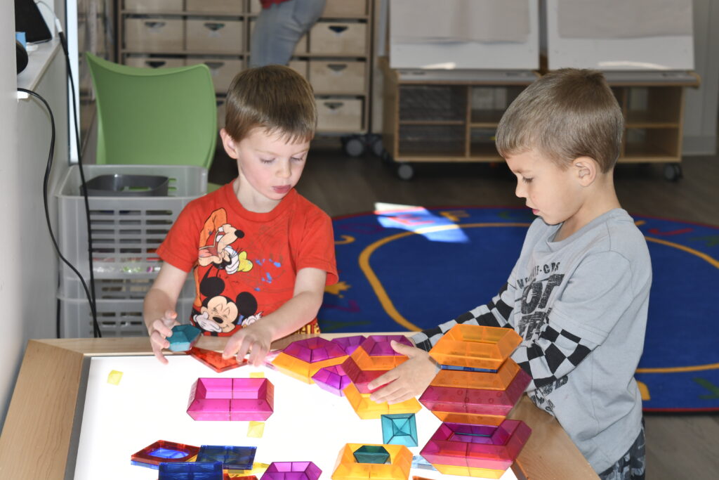 Two boys build on the light table