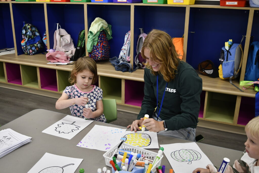 A teacher and student use the stamping gross motor skill to create nature images