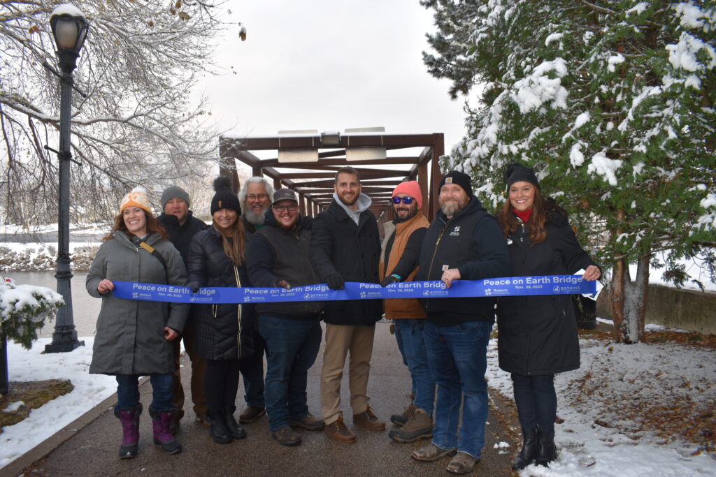 Batavia Park District staff holding a grand opening ribbon for the Peace Bridge.