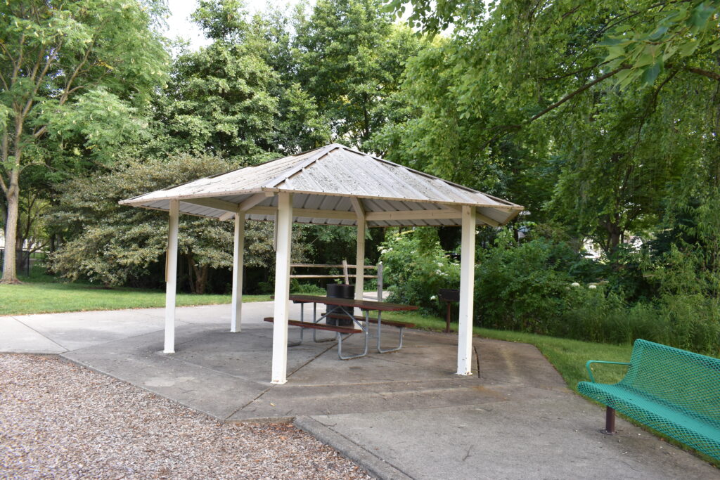 Braeburn Park and Preserve pavilion showing a picnic table, bench and trash can.