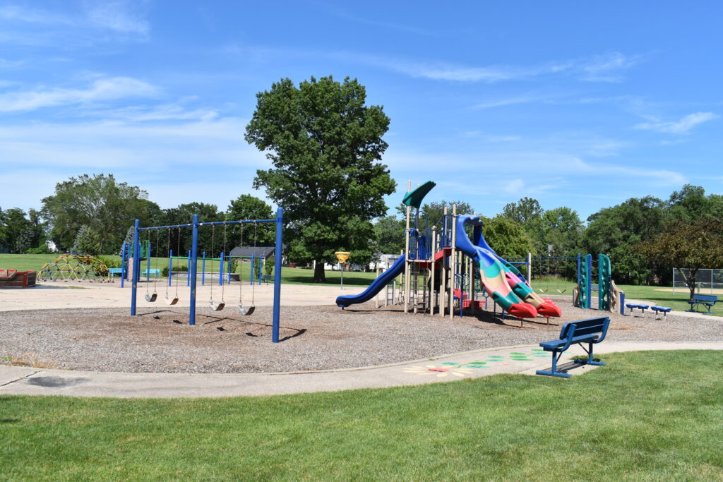 Prairie and Lathem Park playground showing slides, swings and a bench that overlooks the park.