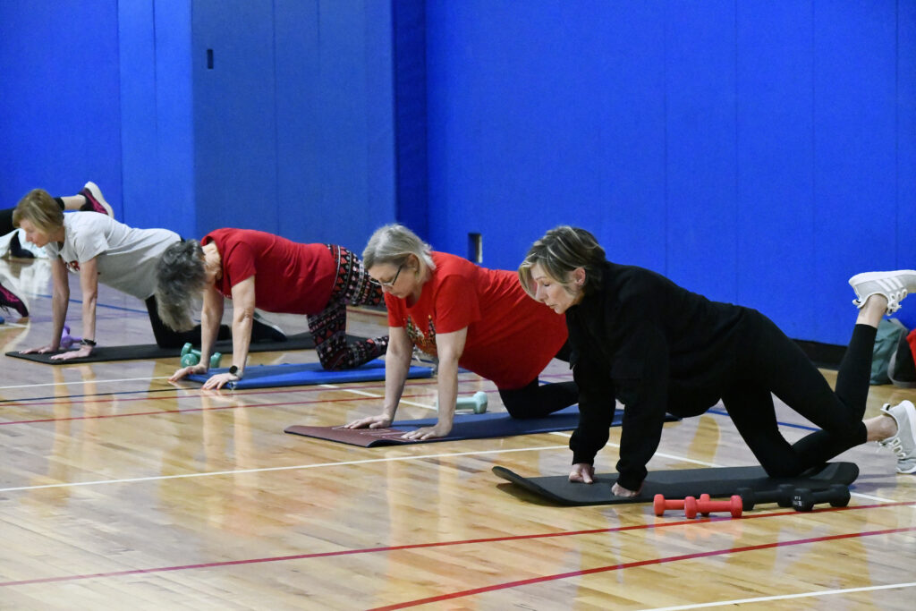 Women practice a glute kickback during a fitness class