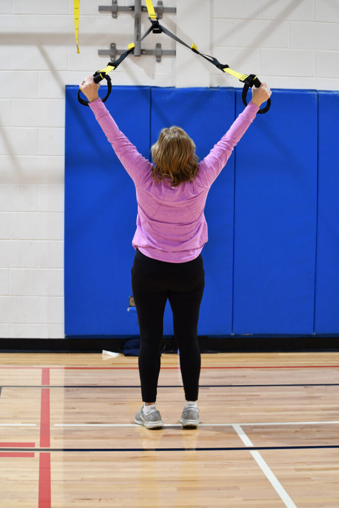 A woman stretches with TRX straps during a TRX fitness class