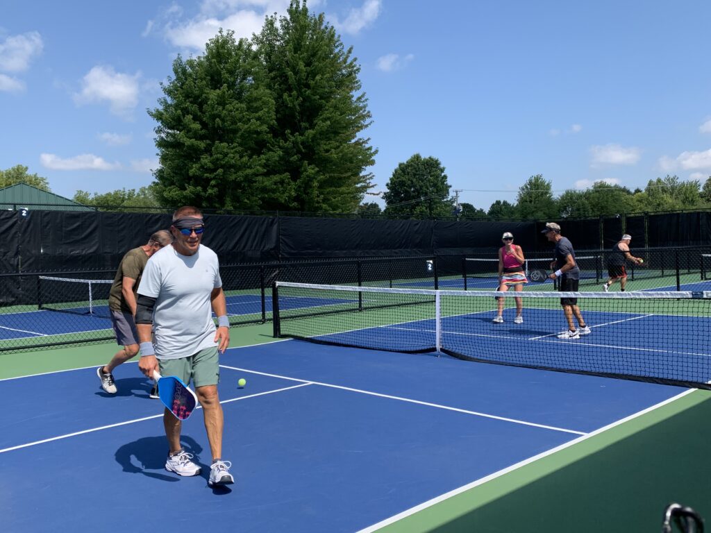 A group of four pickleball players in a match at the outdoor pickleball court at West Main Community Park in summer