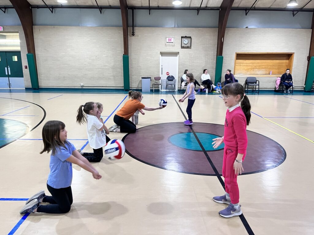 A group of young girls practice serving the ball at volleyball lessons at the Eastside Community Center Gym