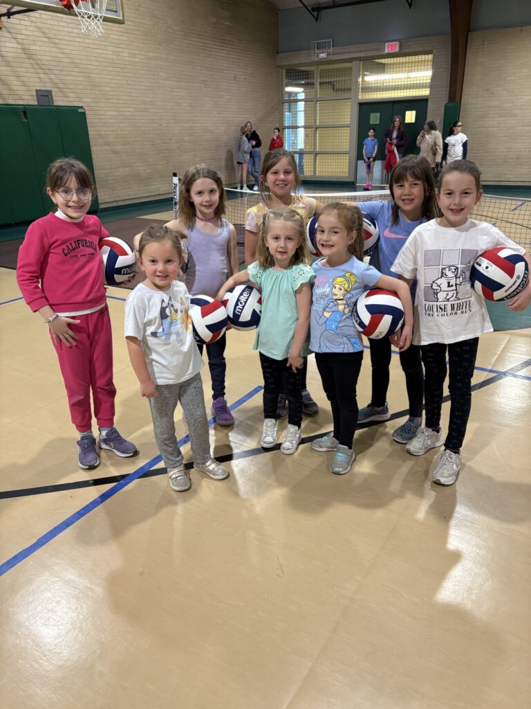 A group of girls 5-8 pose for a photo after volleyball lessons at Eastside Community Center gym