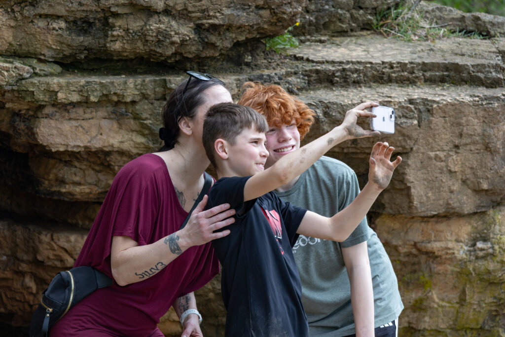 two boys and a mom stop to take a selfie during a hike
