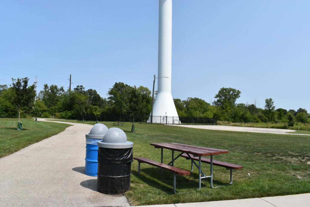 Peter Frieders Park showing open space with a picnic table, and trash and recycling cans next to it.
