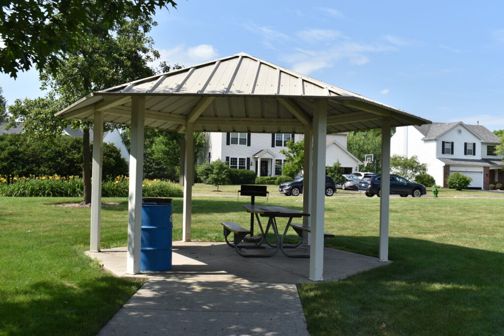 Saratoga Park rentable pavilion with a picnic table and trash can.
