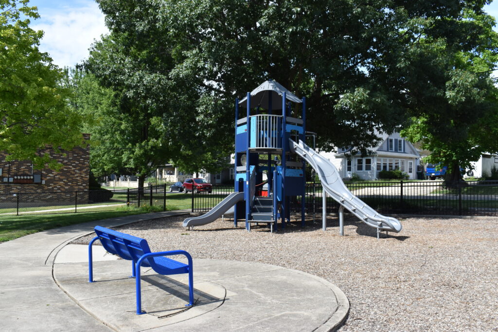 Washington Park showing bench with playground in front of it.