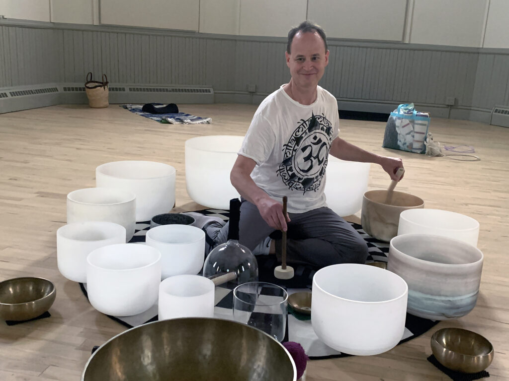 A sound healing instructor plays crystal bowls during a fitness sound healing session