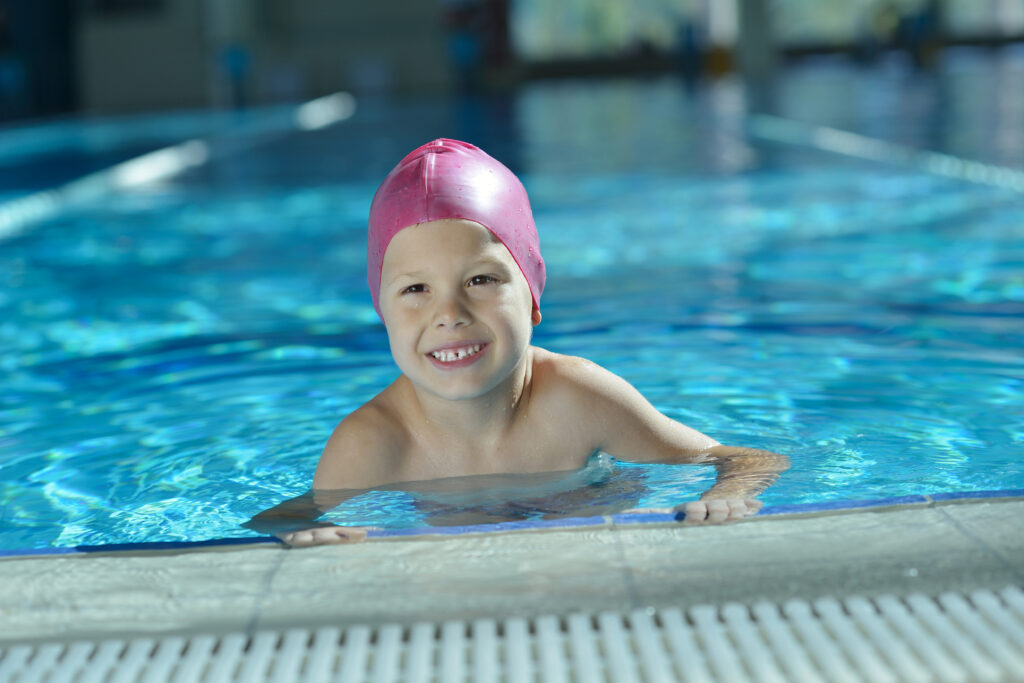 boy smiling in pool during indoor swim lessons