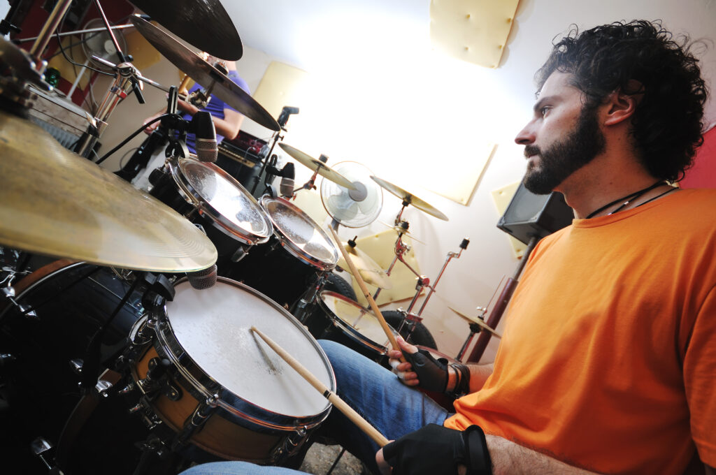 man practicing playing the drums on a drum kit