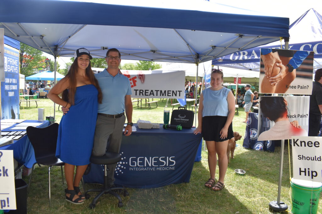 Three people standing in front and to the side of a table at an outdoor event