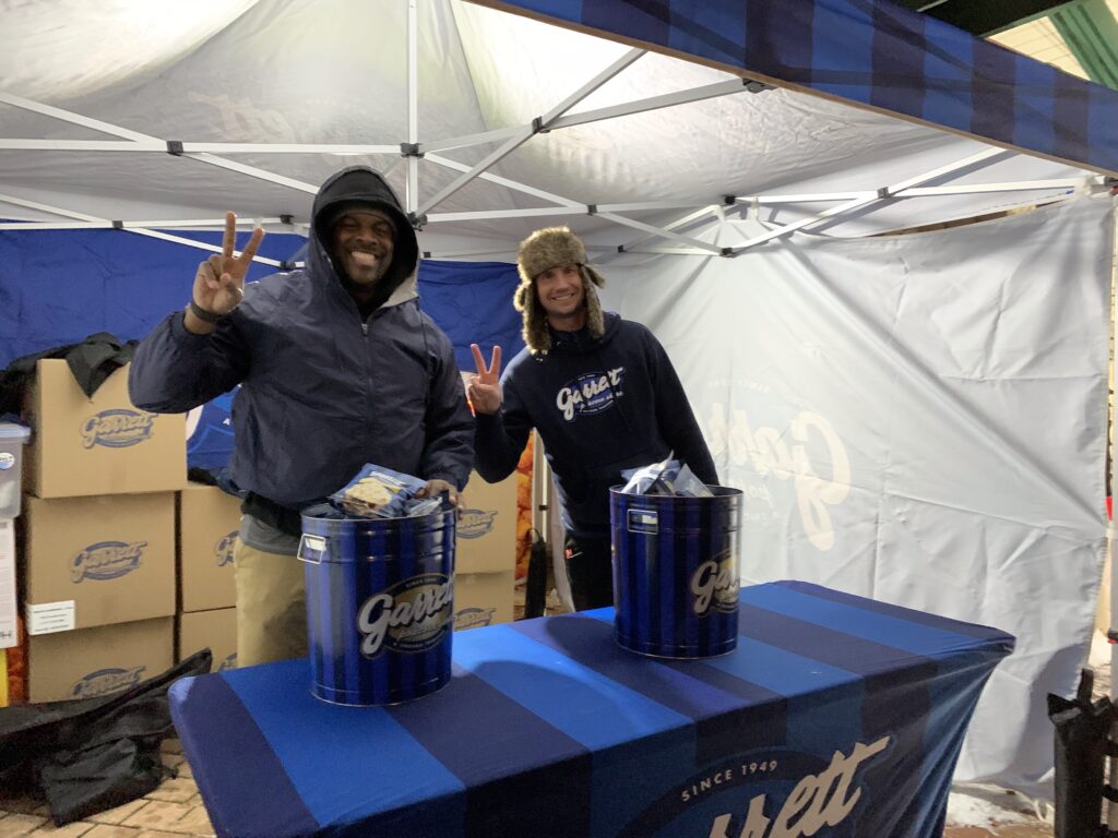 Two people behind table handing out samples
