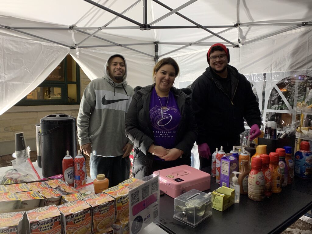 Three people handing out samples behind table